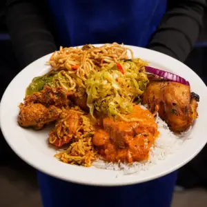 Plate with Indian curries, basmati rice, grilled chicken, noodles, sautéed vegetables, and chutney