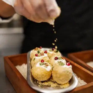 Dahi puri topped with yogurt, chutneys, pomegranate seeds, herbs, and crispy sev