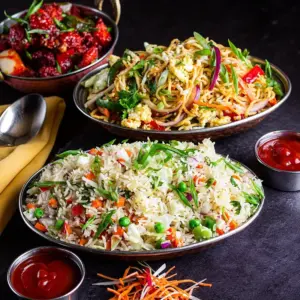 Vegetable fried rice and stir-fried noodles served with a red Indo-Chinese appetizer and dipping sauces